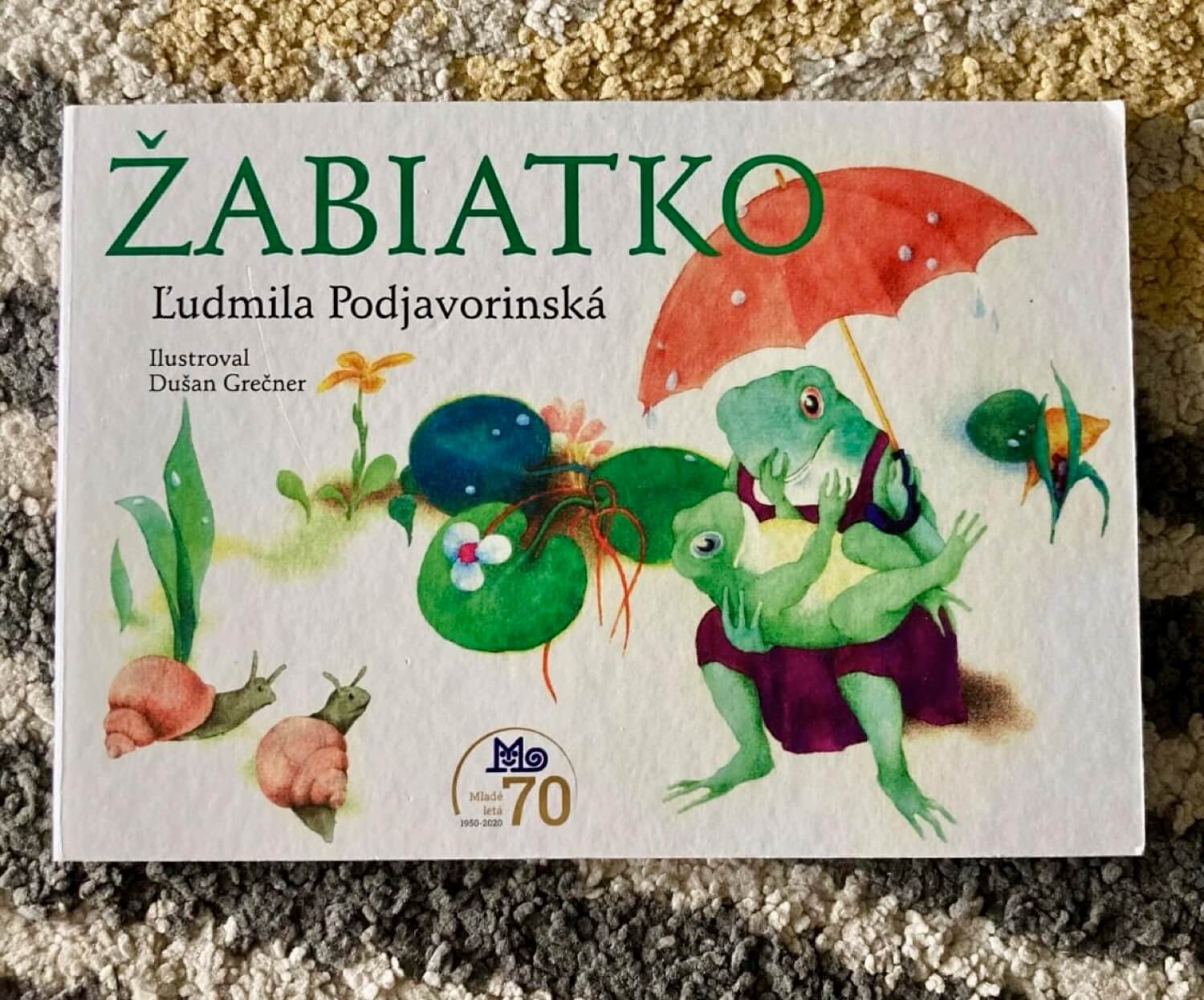 Kniha Žabiatko od Ľudmily Podjavorinskej s ilustráciami Dušana Grečnera patrí medzi obľúbené detské diela slovenskej literatúry. Veselá ilustrácia so žabkami, slimákmi a dáždnikom vystihuje hravú atmosféru príbehu pre deti.